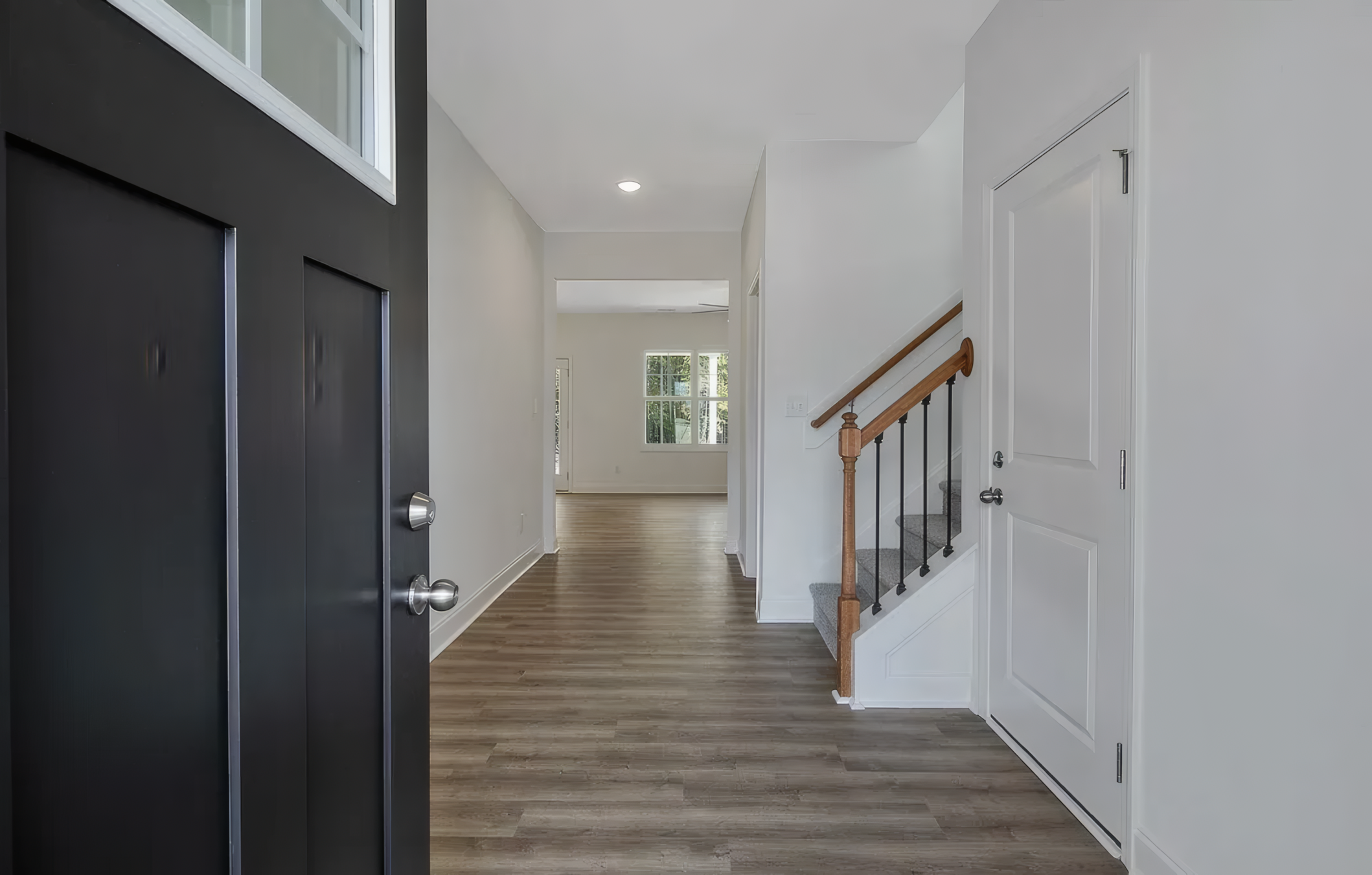 Inside view of house, you can see end of starcase and giant window at the end of the hallway